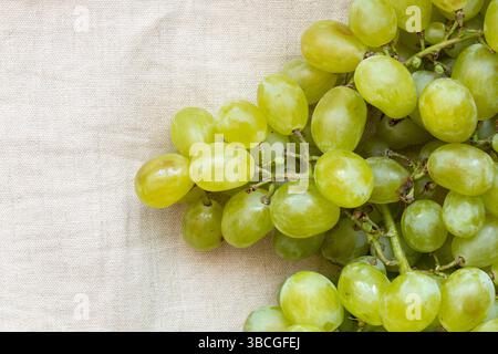Ein Haufen grüner Trauben liegt auf hellbeigem Stoff, Früchten Stockfoto