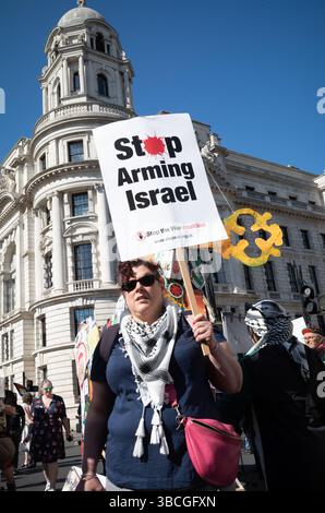 Eine pro-palästinensische Protestlerin hält ein Banner bei einem Marsch für Palästina gegen israelische Angriffe auf Gaza in Zentral-London, Großbritannien. Stockfoto