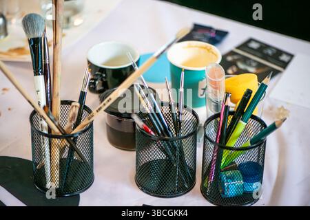 Eine sorgfältig angeordnete Szene mit Malpinseln und Kunstgegenständen auf einem rustikalen Studiotisch. Stockfoto