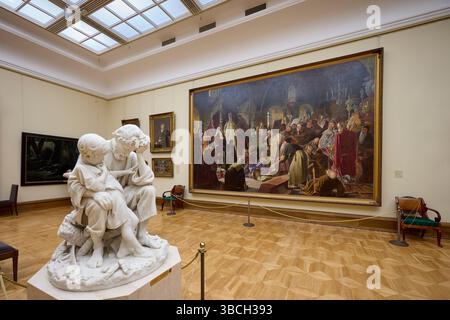 Skulptur „Bauernmann in Schwierigkeiten“ von Matvey Chizhov vor dem Gemälde Debatte über den Glauben (1881) von Wassili Perow. Tretjakow-Galerie, Moskau, Russland. Stockfoto