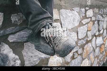 Die Füße eines Touristen ruhen auf einer Steinmauer, in festen Schuhen, draußen Stockfoto