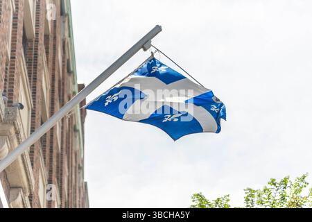Die Flagge von Quebec, die an einem Mast an einem Gebäude hängt. Stockfoto
