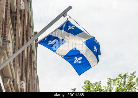 Die Flagge von Quebec, die an einem Mast an einem Gebäude hängt. Stockfoto