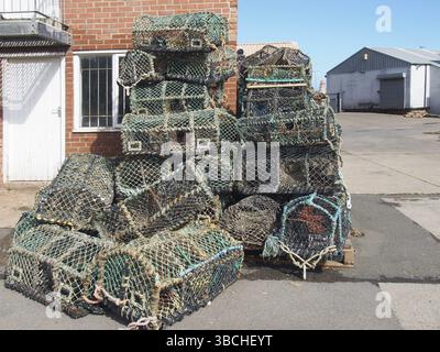 Hummertöpfe, die bei der traditionellen Fischerei auf Krebstiere verwendet werden, stapeln sich an einem Hafengebäude im Hafen von scarborough Stockfoto
