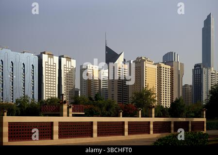 Städtische Skyline mit modernen Wolkenkratzern und einem dekorativen Zaun im Vordergrund unter klarem Himmel. Abu Dhabi, VAE Stockfoto