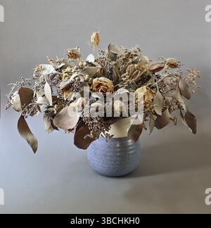 Strauß getrockneter Blüten in Keramikvase auf neutralem Hintergrund Stockfoto