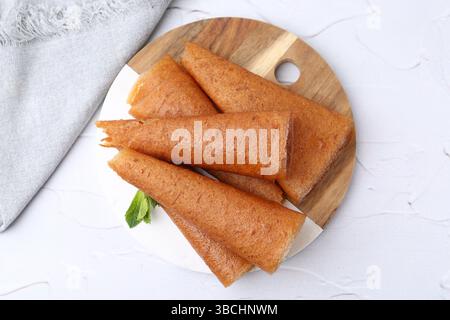 Köstliche Fruchtlederrollen und Minzbonbons auf weißem Tisch, Blick von oben Stockfoto