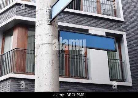 Leere Straßenschilder in der Stadt. Leere blaue Pfeile auf der Stange. Fahrtrichtungsanzeiger im Stadtverkehr. Moderne Architektur im Hintergrund. Navigationskonzept. Kopierbereich Stockfoto