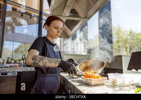 Ein talentierter Koch bereitet in einer eleganten, modernen Küche sorgfältig ein exquisites Gourmetgericht zu Stockfoto