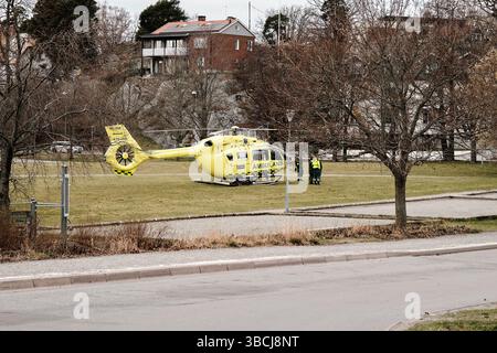 Nynashamn, Schweden - 6. April 2025: Ein gelber und grüner Hubschrauber mit dem Wort Ambulance an der Seite in einem schwedischen Park. Die Flugbesatzung wartet auf den Patienten Stockfoto