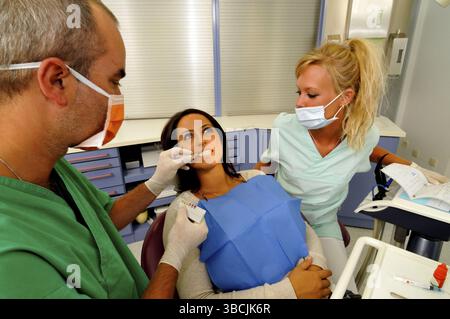 Zahnarzt behandelt Patienten, Patienten, Zahnarzthelfer, Behandlung, Gesichtsmaske Stockfoto