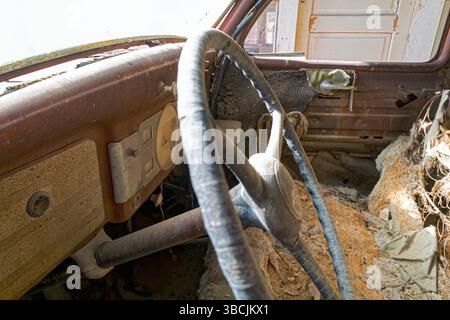 Das Armaturenbrett und das zerfallene Interieur eines antiken Autos, das in der Wüste verlassen wurde Stockfoto
