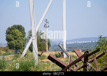Straße, Stangen mit Drähten und Panzerabwehrigel in der Nähe der Straße vor dem Hintergrund der Stadt, Krieg in der Ukraine, Verteidigung der Stadt Stockfoto