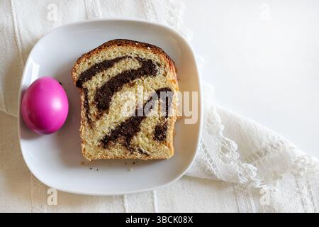 Cozonac, traditionelles rumänisches Osterbrot-Dessert. Ein Stück süßes Brot und Ostereier auf weißem Hintergrund. Osterferienkonzept. Stockfoto