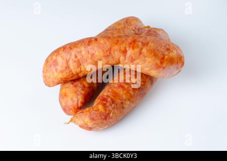Drei rohe geräucherte Würstchen auf weißem Hintergrund in Studiobeleuchtung für Lebensmittelverpackungen, Werbung und kulinarische Zwecke Stockfoto