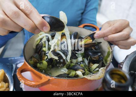 Horizontale Ansicht der Hände einer Frau, die traditionelle Muschel und Pommes Frites-Gericht isst Stockfoto