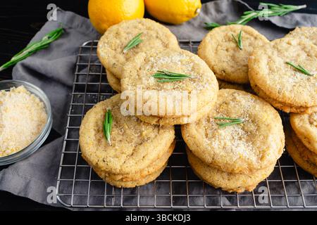 Rosmarin-Lemon Sugar Cookies gestapelt auf einem Drahtgestell: Schräge Nahaufnahme von Stapeln frisch gebackener selbstgemachter Zuckerkekse auf einem Drahtgestell Stockfoto
