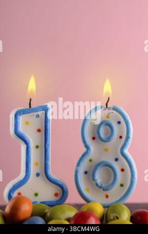 Geburtstagskerzen mit der Nummer 18 auf einem rosa Hintergrund mit Platz für text Stockfoto