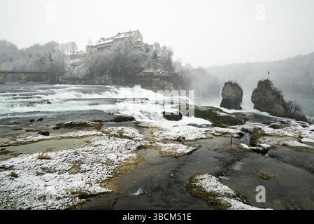 Landschaftsbild des Rheinfalls Wasserfalls in der Schweiz an einem Wintertag mit Schneefall Stockfoto