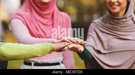 Vereinigte Muslimische Frauen In Hijab Hände Halten Im Freien Stehend, Abgeschnitten Stockfoto