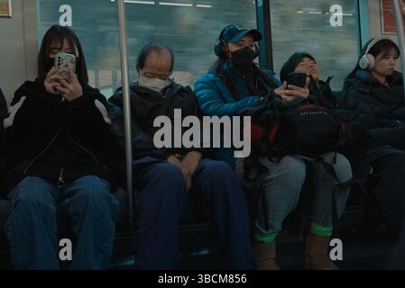 Passagiere in ihrer eigenen Welt – einige schlafen, andere scrollen – auf einer ruhigen U-Bahn-Fahrt Stockfoto