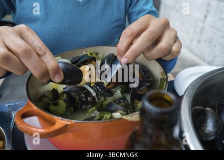 Horizontale Ansicht der Hände einer Frau, die traditionelle Muschel und Pommes Frites-Gericht isst Stockfoto