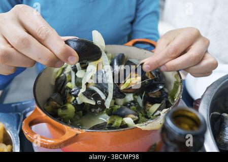 Horizontale Ansicht der Hände einer Frau, die traditionelle Muschel und Pommes Frites-Gericht isst Stockfoto