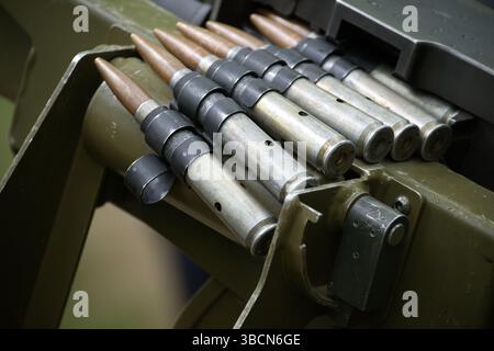 Aus nächster Nähe zeigt Maschinengewehrkugeln, aufgereiht, einsatzbereit, in einer Militärwaffe. Stockfoto