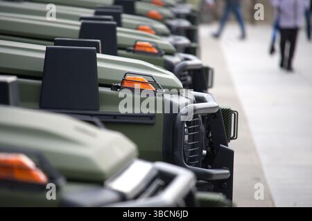 Eine abgewinkelte Perspektive auf mehrere Fahrzeuge im Militärstil, die in einer geordneten Anordnung auf einer gepflasterten Fläche geparkt sind. Stockfoto