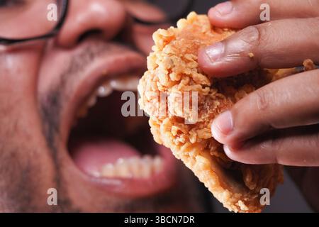 Person, die knuspriges gebratenes Huhn in Nahaufnahme genießt Stockfoto