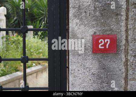 Haus Nr. 27 steht auf einer Steinmauer in einem Garten Stockfoto