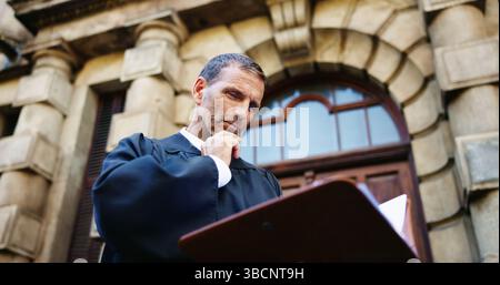 Denken, lesen und beurteilen und reifer Mann in der Stadt für Gerichtsbericht, Politikgesetzgebung und Rechtsdokumente. Anwaltsidee, Anwaltspapiere und Stockfoto