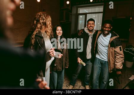 Gruppe von Freunden, die einen fröhlichen Abend in einem gemütlichen Ort mit sanfter Beleuchtung und Lachen genießen Stockfoto