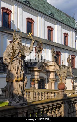 Steinstatue mit goldenem Kreuz vor dem Broumov-Kloster in Broumov, Tschechische Republik Stockfoto