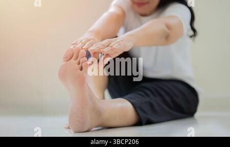 Seien Sie flexibel. Nahaufnahme einer entspannten Frau, die in Yoga-Pose sitzt und ihren Körper dehnt, während sie zu Hause auf dem Boden Yoga macht. Stockfoto