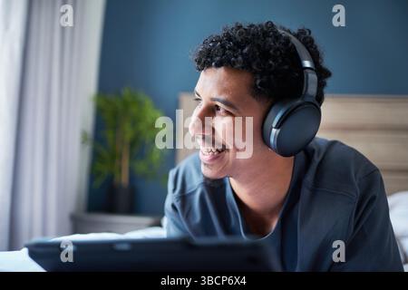 Junger Mann, der Musik mit schnurlosen Kopfhörern in einem komfortablen Zuhause hört Stockfoto