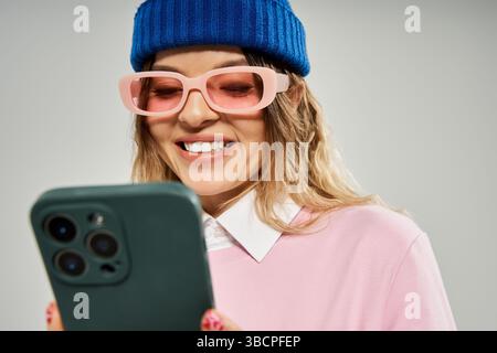 Eine hübsche junge Frau genießt ihre Zeit in einem Studio, während sie ihr Handy benutzt und lächelt. Stockfoto