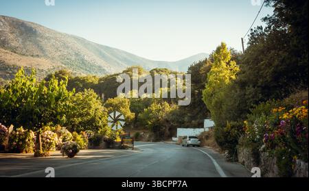 Fahrt um das Lasithi-Plateau. Leere Bergstraße am Nachmittag - aus Sicht des Fahrers. Schmale Straße in montaner ländlicher Gegend mit vielen Bäumen. Stockfoto
