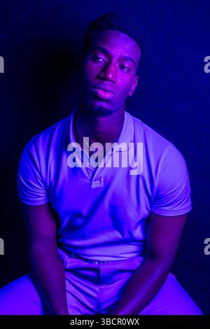 Studio-Porträt eines jungen Mannes, der in blaues Licht getaucht ist und eine dramatische und atmosphärische Stimmung erzeugt Stockfoto