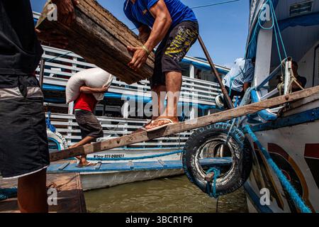 Hafenarbeiter im Hafen von Santarém in Pará, Brasilien, laden handwerklichen Kautschuk aus den Amazonaswäldern auf ein traditionelles Flussboot. Stockfoto
