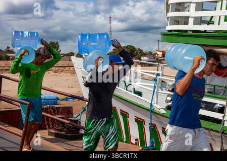 Hafenarbeiter laden Trinkwasser in Pará, Brasilien, auf traditionelle Amazonas-Flussläufe im Hafen von Santarém. Stockfoto
