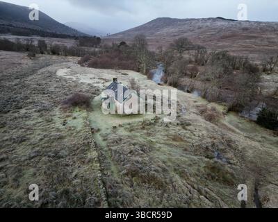 Blick aus der Vogelperspektive auf Invermallie Bothy in den abgelegenen schottischen Highlands – ein Bergheim, eingebettet an einem gewundenen Fluss in einer wilden, frostigen Landschaft Stockfoto