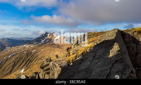 Ein einsamer Fotograf steht auf dem Cobbler (Ben Arthur) in den schottischen Arrochar-Alpen und hält die dramatischen Ausblicke von einem der berühmtesten Gipfel fest. Stockfoto