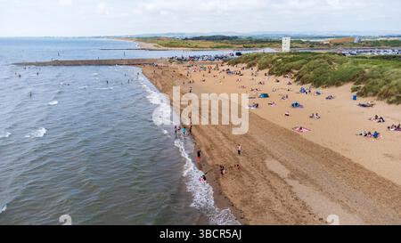 Aus der Vogelperspektive auf Irvine Beach an einem Sommertag, bei dem Familien und Besucher die sandige Küste von Ayrshire im Südwesten Schottlands genießen Stockfoto