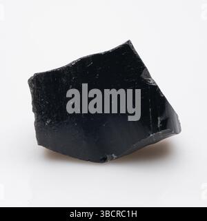 Volcanic Glass Fragment: Ein rohes Obsidianstück, das eine dunkle, glänzende Oberfläche und einen winkligen Bruch aufweist - eine natürliche Felsformation für die Geologie-Studie. Stockfoto