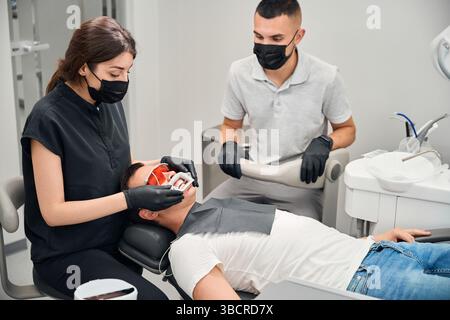 Erfahrener Stomatologe, der den Mundöffner auf den männlichen Klienten einstellt Stockfoto