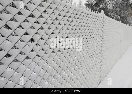 Maschendrahtzaun bedeckt mit Schnee an kalten Wintertagen. Stockfoto