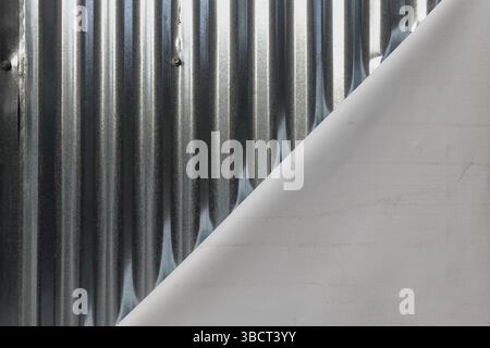 Gewellter Blechzaun und gefaltetes weißes Leinwandmaterial Hintergrundstruktur. Stockfoto