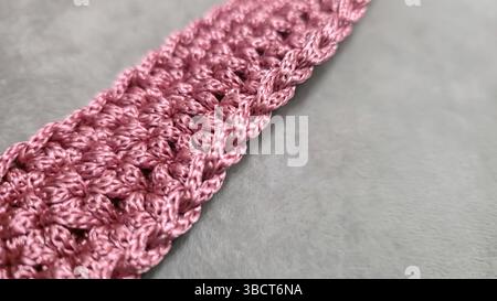 Stricken von Elementen einer rosafarbenen Damentasche, Handstricken mit langem Griff. Schritt-für-Schritt-Anweisungen. Auf grauem Hintergrund. Stockfoto
