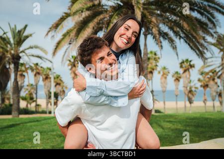 Ein fröhliches Paar genießt einen verspielten Huckepack-Ritt und strahlt Glück und Freude in ihrem unbeschwerten Moment zusammen aus. Stockfoto